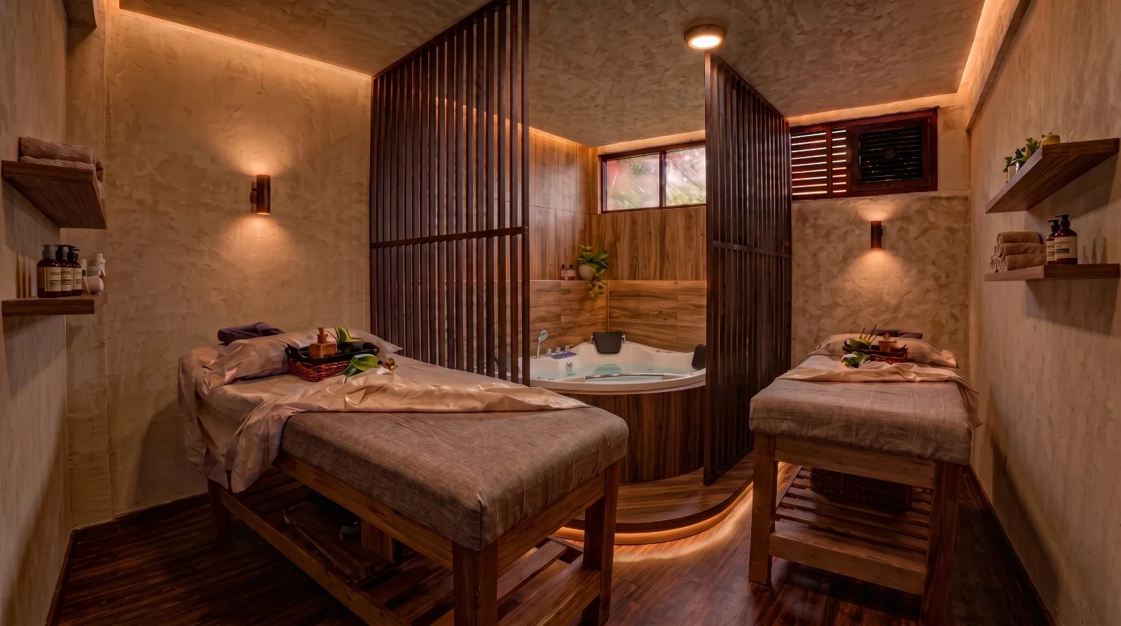 Sala de masajes para dos personas con camillas de madera y jacuzzi esquinero detrás de una celosía, en Spa Cusco inLove